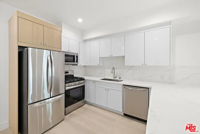 a kitchen with stainless steel appliances granite countertop a refrigerator sink and white cabinets