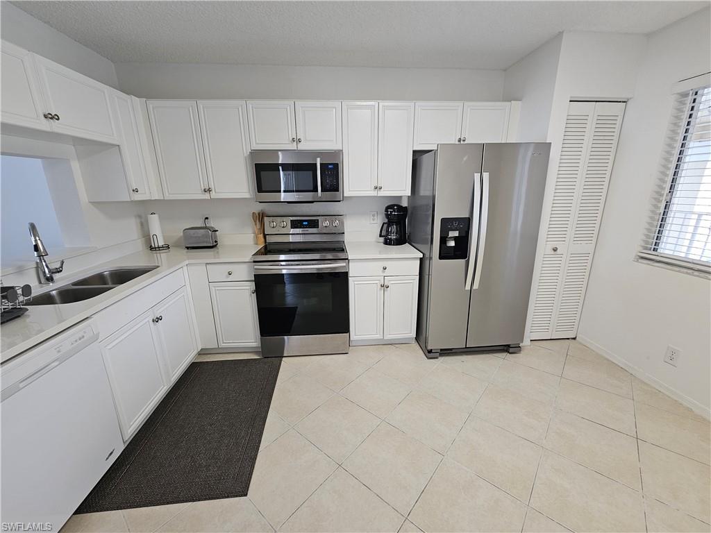 7766 Emerald Circle, Unit R201 Naples, FL 34109 - Photo 12 of 35 a kitchen with stainless steel appliances a refrigerator stove microwave and sink