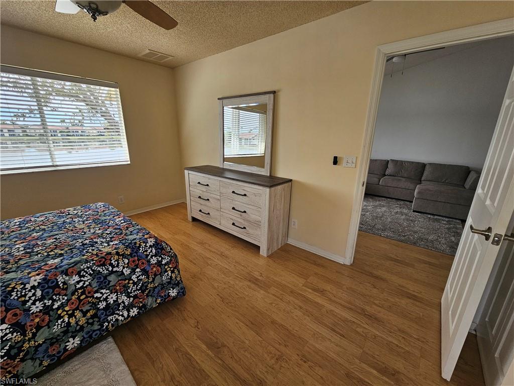 7766 Emerald Circle, Unit R201 Naples, FL 34109 - Photo 14 of 35 a bedroom with a bed and wooden floor