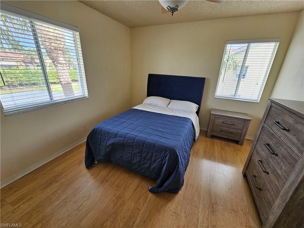 7766 Emerald Circle, Unit R201 Naples, FL 34109 - Photo 15 of 35 a bedroom with a bed and wooden floor