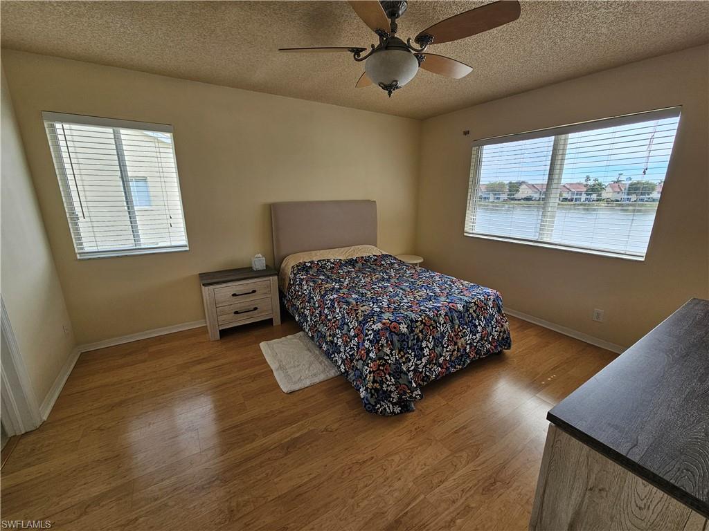 7766 Emerald Circle, Unit R201 Naples, FL 34109 - Photo 16 of 35 a bedroom with a bed and wooden floor