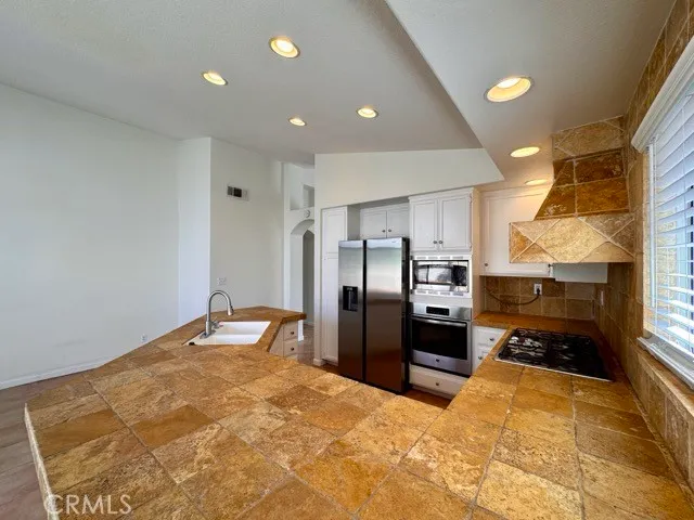 a large kitchen with stainless steel appliances a refrigerator and a stove top oven