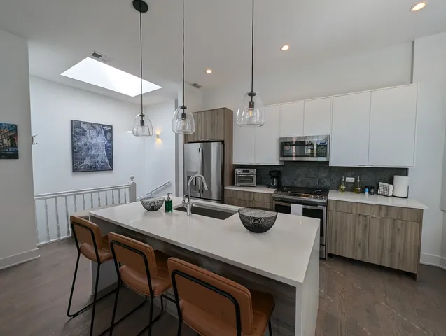 a kitchen with stainless steel appliances granite countertop a kitchen island a stove a table and chairs