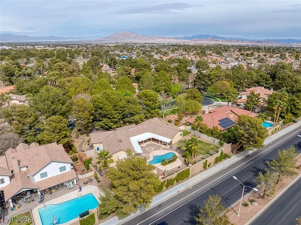9 Quail Run Road Henderson, NV 89014 - Photo 49 of 57 An aerial panorama reveals multiple private pools amidst lush greenery and distant mountain vistas.
