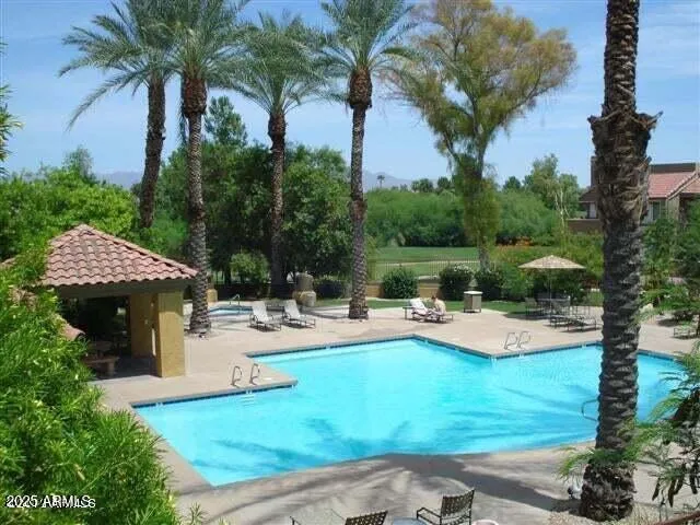 a view of a swimming pool with chairs and table in the patio
