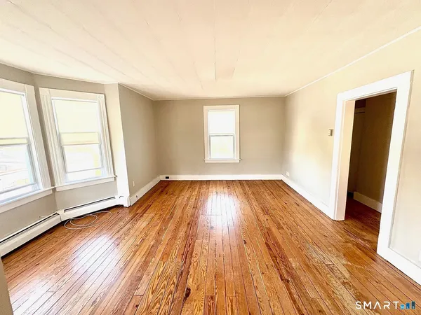 an empty room with wooden floor and windows