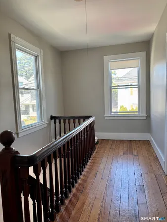 a view of hallway with wooden floor and fan