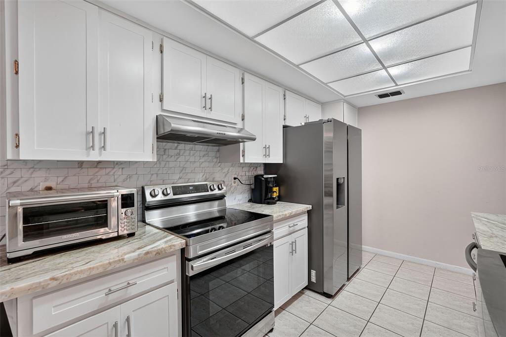 3602 Player Drive New Port Richey, FL 34655 - Photo 10 of 42 a kitchen with stainless steel appliances granite countertop a refrigerator stove and cabinets