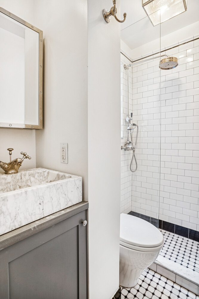 101 Thompson Street, Unit 19 Manhattan, NY 10012 - Photo 5 of 6 a bathroom with a granite countertop sink a toilet and shower