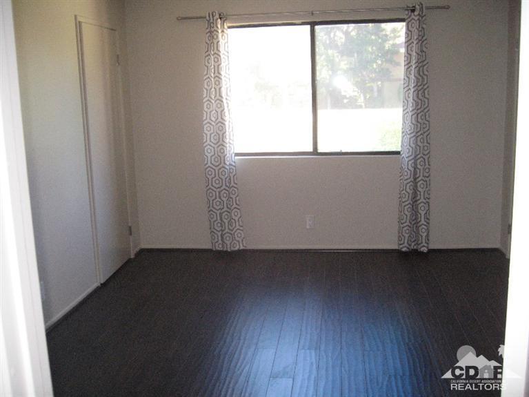200 East Racquet Club Road, Unit 52 Palm Springs, CA 92262 - Photo 8 of 28 an empty room with wooden floor and windows