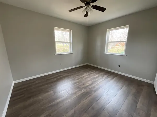 a view of a big room with wooden floor and windows