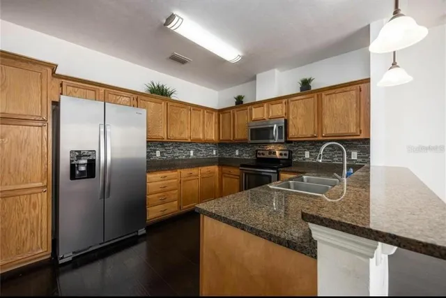 a kitchen with granite countertop stainless steel appliances a refrigerator a stove top oven a sink and a center island