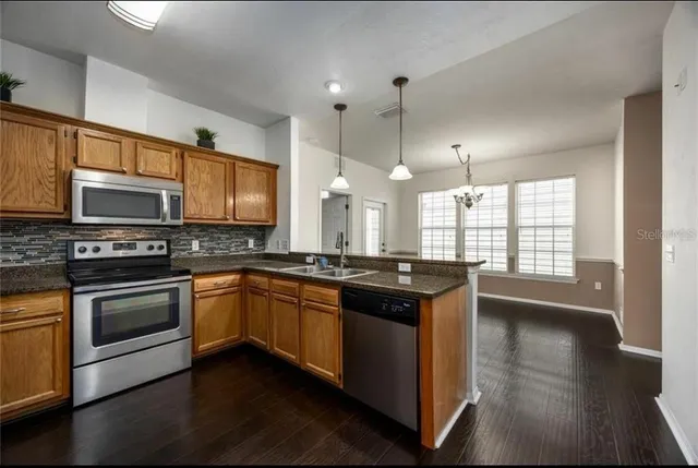 a kitchen with stainless steel appliances granite countertop a stove a sink and a microwave