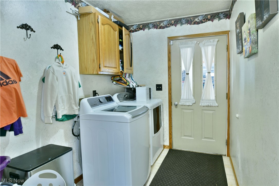 5915 Downs Road Northwest Warren, OH 44481 - Photo 26 of 50 Laundry room with cabinets, washing machine and dryer, a textured ceiling, and light tile patterned floors