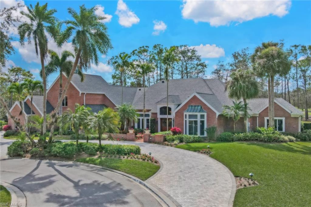 4556 Silver Fox Drive Naples, FL 34119 - Photo 2 of 22 a front view of a house with a garden and tree