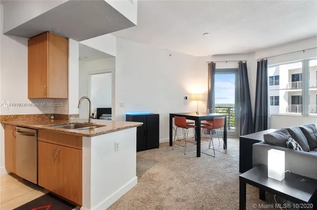 a open kitchen with stainless steel appliances granite countertop a stove top oven a sink a dining table and chairs with wooden floor