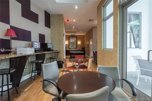 a room with stainless steel appliances a dining table chairs and a refrigerator