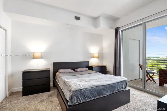 a bedroom with a bed and a lamp on dresser