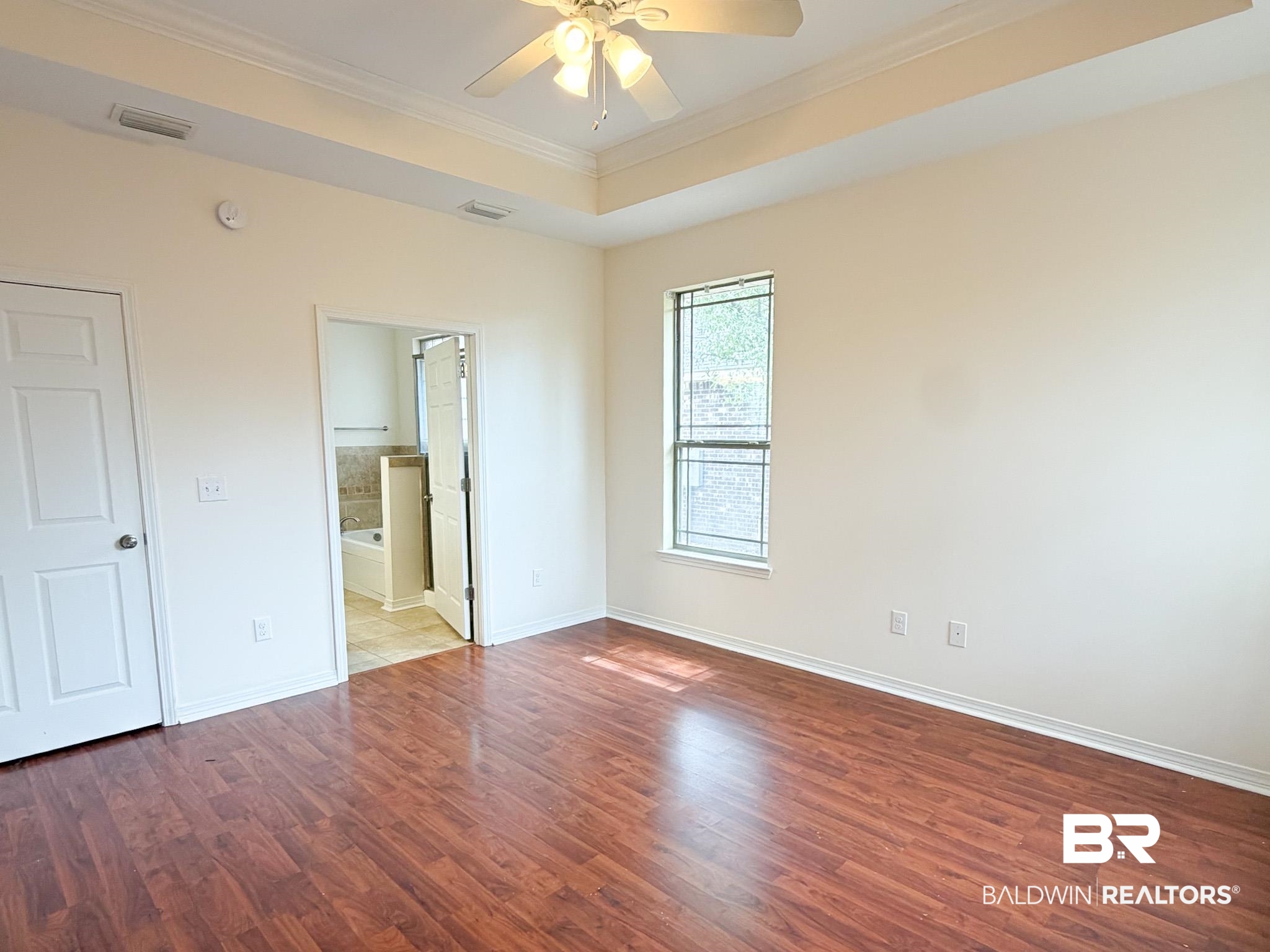 7332 Raintree Lane Gulf Shores, AL 36542 - Photo 10 of 21 Unfurnished bedroom featuring ornamental molding, ceiling fan, dark wood finished floors, a tray ceiling, and ensuite bathroom