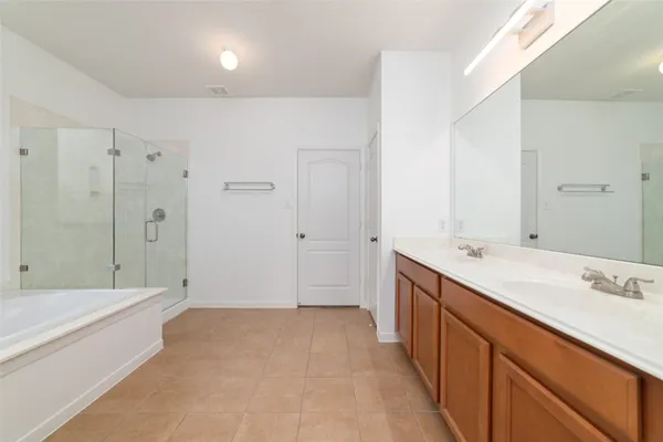 a spacious bathroom with a tub sink and mirror