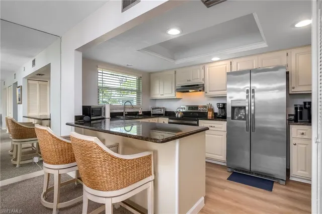 a kitchen with granite countertop stainless steel appliances a sink a counter top space and a window