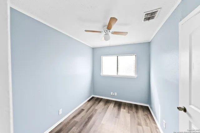 a view of room with window ceiling fan and hardwood floor