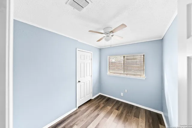 a view of an empty room with wooden floor and a window