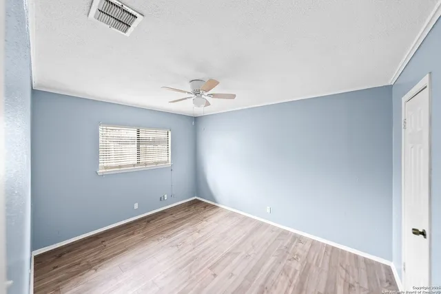 an empty room with a window and ceiling fan