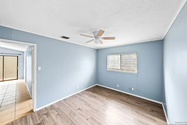 a view of a room with wooden floor and a ceiling fan