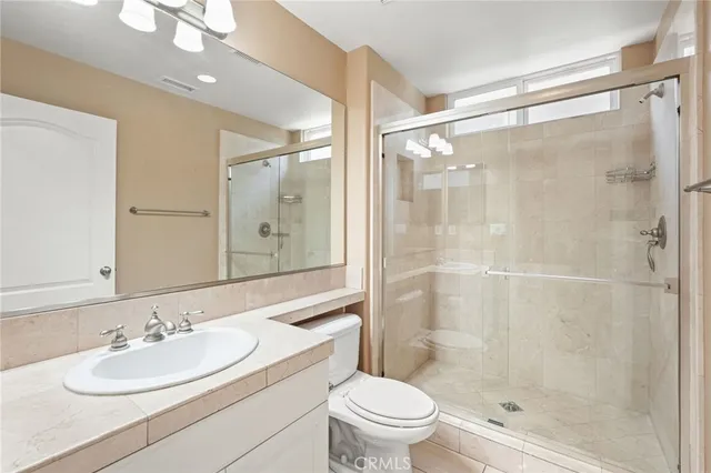 a bathroom with a sink vanity granite toilet and shower