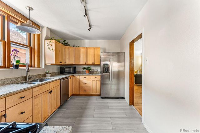 a large kitchen with a refrigerator a sink dishwasher a stove and white cabinets with wooden floor