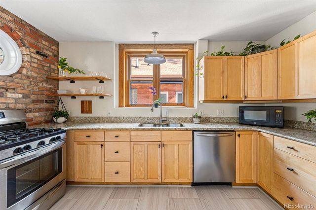 a kitchen with granite countertop a sink cabinets stainless steel appliances and a window