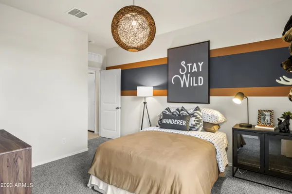 a bedroom with a bed and a lamp on dresser