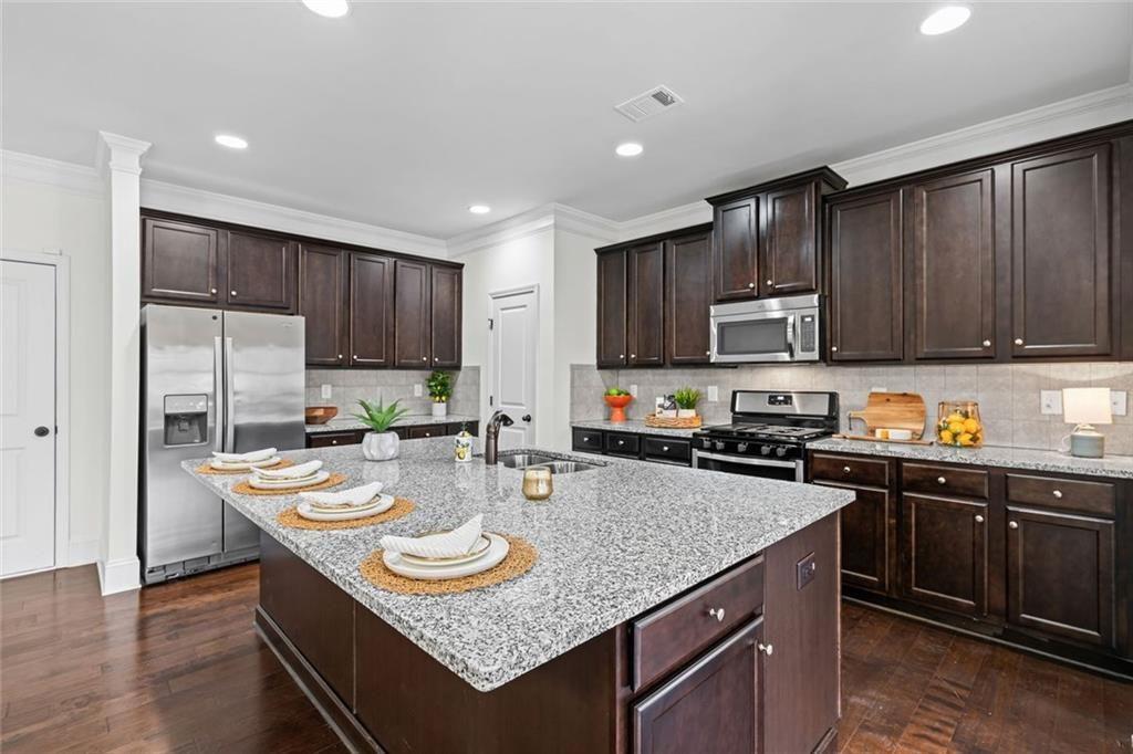 3915 Estates Path Cumming, GA 30040 - Photo 20 of 50 a kitchen with kitchen island granite countertop stainless steel appliances a sink stove and refrigerator