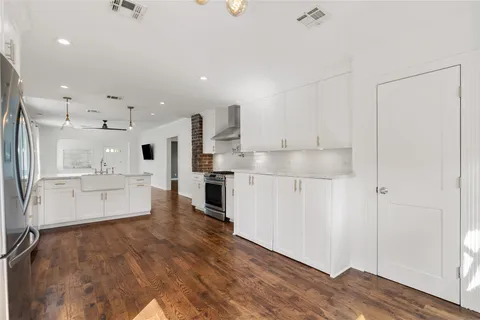 a large white kitchen with white cabinets and wooden floor