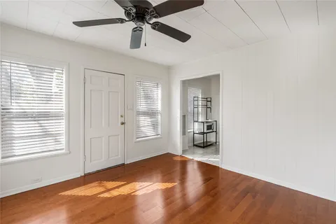 a view of an empty room with a window and wooden floor