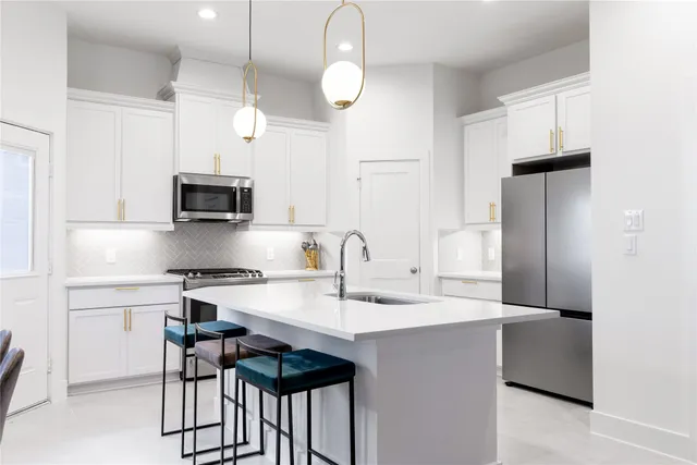 a kitchen with kitchen island granite countertop a sink cabinets and stainless steel appliances