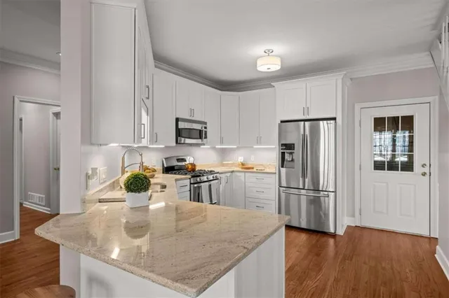 a kitchen with refrigerator a stove a sink and white cabinets