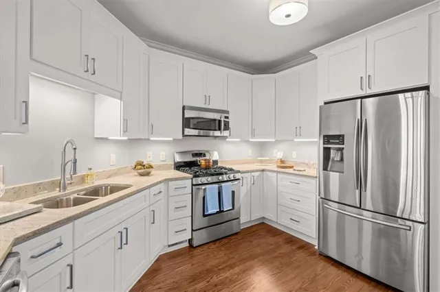 a kitchen with cabinets stainless steel appliances a sink and wooden floor