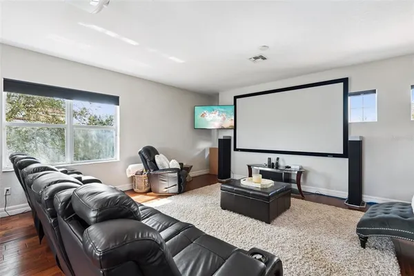 a living room with furniture a flat screen tv and floor to ceiling window