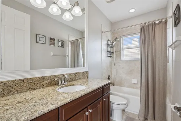 a bathroom with a granite countertop sink a toilet a mirror and shower