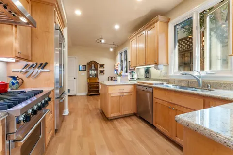 a kitchen with stainless steel appliances granite countertop a lot of counter space and wooden floors