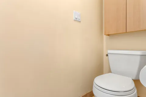 a white toilet sitting next to a white wall