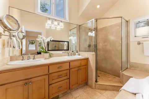a bathroom with a double vanity sink mirror and shower