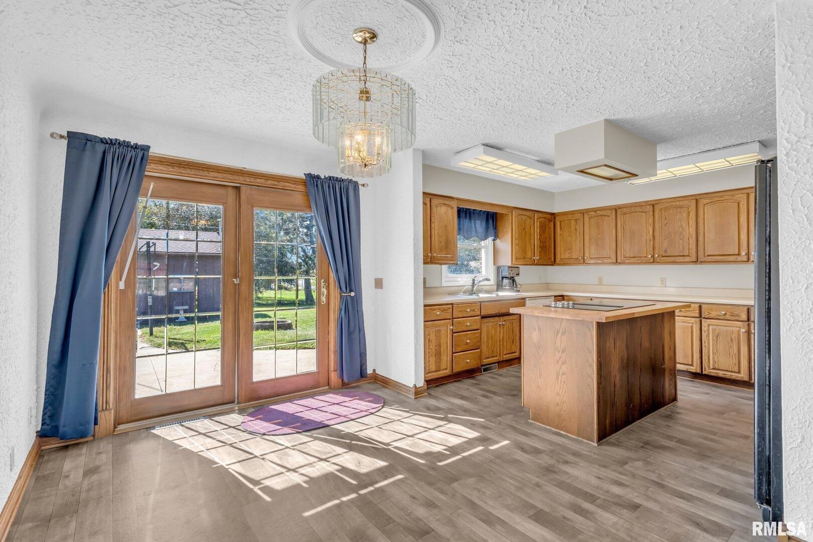 107 Hilltop Street Colona, IL 61241 - Photo 5 of 25 a kitchen with stainless steel appliances granite countertop a refrigerator a sink dishwasher a stove and a dining table with wooden floor