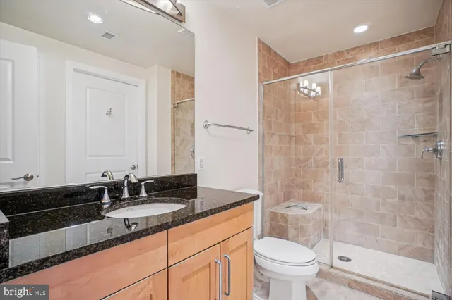 a bathroom with a granite countertop sink toilet and shower