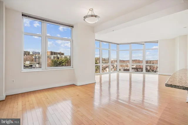 a view of empty room with wooden floor and floor to ceiling window