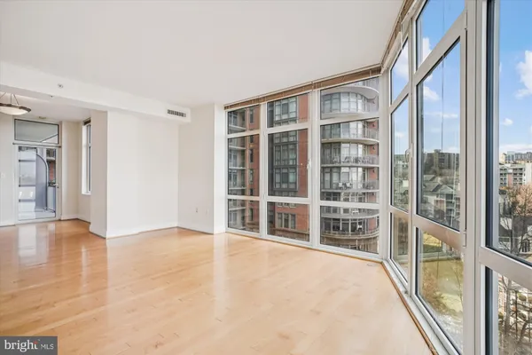 a view of an empty room with wooden floor and windows