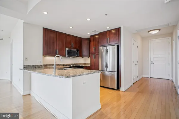 a kitchen with stainless steel appliances granite countertop a refrigerator a sink a stove and oven