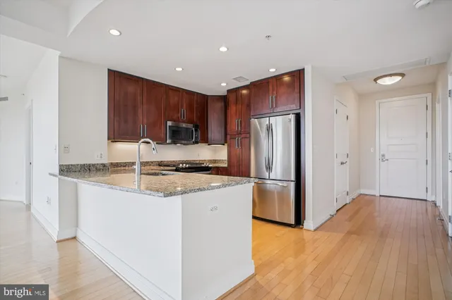 a kitchen with stainless steel appliances granite countertop a refrigerator a sink a stove and oven